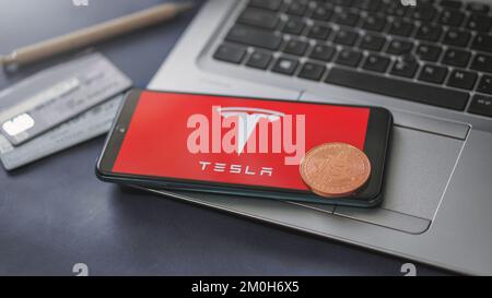 Dobrich, Bulgaria – 2022, November, 26: Mobile phone on a laptop with the Tesla logo, Bitcoin and credit cards. Illustrative editorial concept Stock Photo