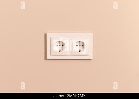 Group of white european electrical outlets on modern beige wall Stock Photo