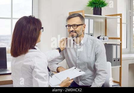 Female doctor therapist in white coat talking to male patient Stock Photo