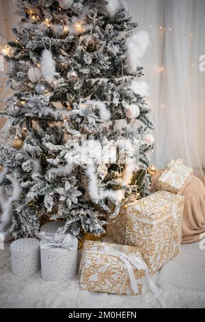 Beautiful Christmas gift boxes on floor near fir tree in room Stock Photo