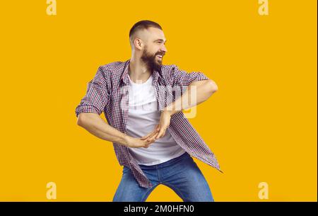 Happy young man in casual clothes dancing isolated on a yellow orange background Stock Photo