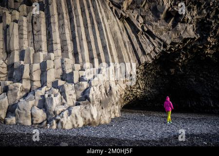 Iceland, Sudurland region, Reynisfjara beach, geometric basalt columns at the foot of Reynisfjall mountain which separates Vik from Reynisfjara, figure in front of H?lsanefshellir, a cave accessible only by low tide Stock Photo