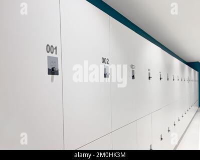 Gym Locker Room, Lockers , Dressing Room. Closed cabinets with white wooden doors starting from number 1 Stock Photo