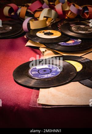 A pile of old fashioned 45 single vinyl records and coloured paper chain. Stock Photo