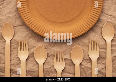 Wooden forks and spoons and paper plate on crumpled paper Stock Photo