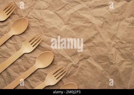 Set of wooden forks and spoons on crumpled paper background Stock Photo