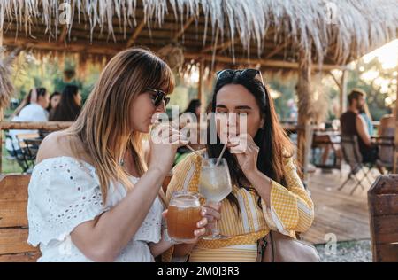 A selective focus shot of two friends drinking cocktails on vacation Stock Photo