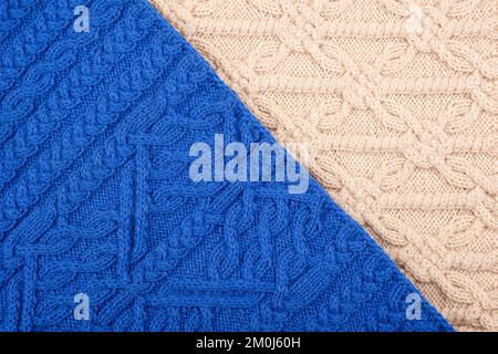 Knitted blue and beige background. Large knitted fabric with a pattern. Close-up of a knitted blanket. Stock Photo