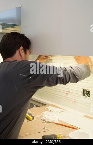 Construction - Installation of Backsplash in Kitchen Remodel Stock Photo