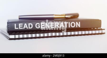Business and education concept. On the table are a notebook, a pen and a book. The book says - LEAD GENERATION Stock Photo