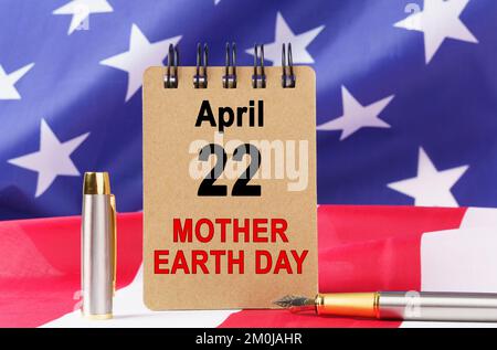 USA Holidays. Against the background of the US flag lies cardboard with the inscription - MOTHER EARTH DAY Stock Photo