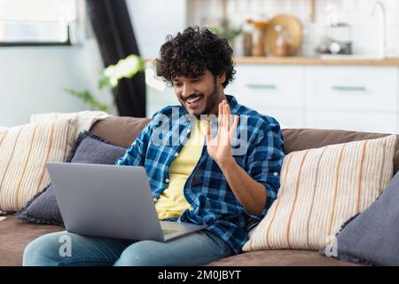 Indian man relaxing on the couch using video call to chat with friends online at home Stock Photo