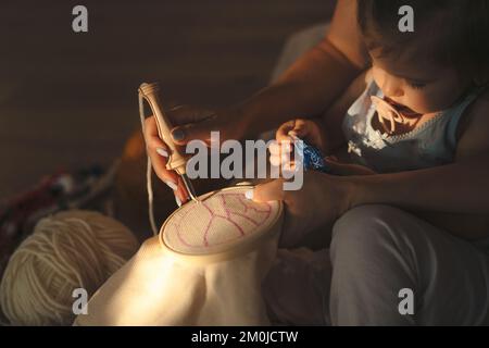 Young woman pushing punchneedle straight down into embroidery canvas. Punch needle embroidery for beginners Stock Photo