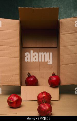 Ripe red pomegranates on the table in a cardboard box Stock Photo