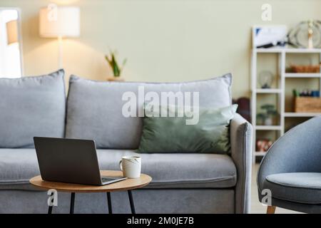 Close up of laptop on coffee table in stylish living room interior with comfortable furniture, copy space Stock Photo