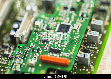 Close up of green printed circuit board with electronic components and microchips in shallow depth of field. Stock Photo
