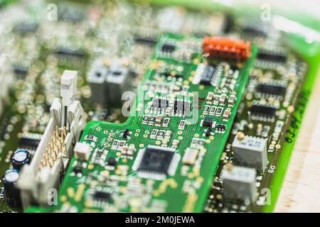 Close up of green printed circuit board with electronic components and microchips in shallow depth of field. Stock Photo