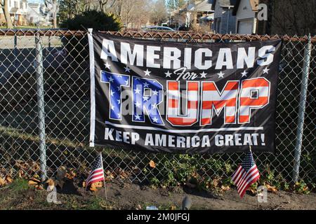 Closeup of an Americans for Trump flag on a fence with two small US flags in front of it in Des Plaines, Illinois Stock Photo