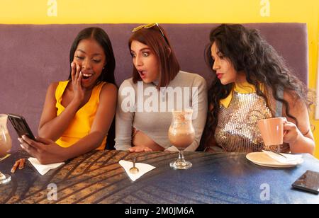 A group of three female friends at a cafe taking selfies and having fun Stock Photo