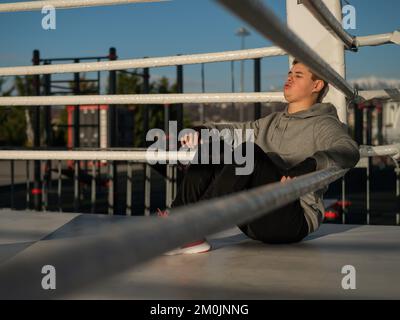 Caucasian male boxer resting in the ring outdoors.  Stock Photo