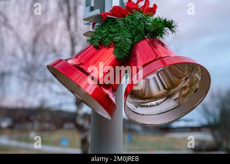 Two large Christmas red bells with red bow and pine leaves , street Christmas decoration, close up view, blurry background Stock Photo