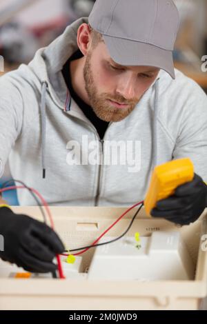 technician checking broken device at table in repair shop Stock Photo