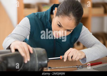 concentrated female repairman repairing something Stock Photo