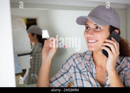 happy female builder with screwdriver talking on smartphone Stock Photo