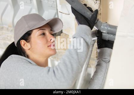 young female plumber fixing a pipe Stock Photo