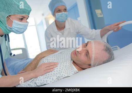 male patient lying in hospital bed recovering after surgery Stock Photo