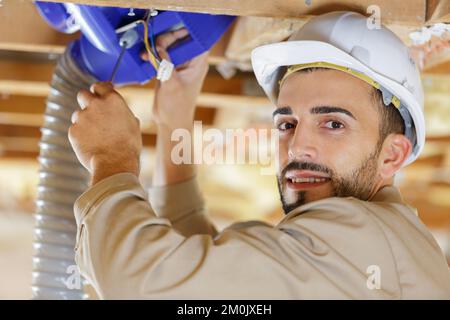 builder examines ventilation in the ceiling Stock Photo