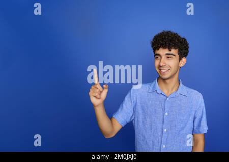 Amazed surprised emotions of young teenager boy. Impressed teenage boy showing recommendation copyspace. Child teenager points away, pointing aside at Stock Photo