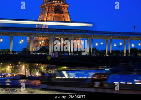 A closed up view of Eiffel Tower at night with a Metro train passing through Pont de Bir-Hakeim Bridge over Seine River in foreground.Paris.France Stock Photo