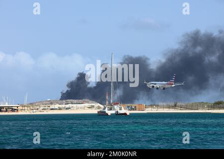 ORANJESTAD, ARUBA - APRIL 07, 2022: Airplane landing at Queen Beatrix Airport while trash is being burnt at Serlimar dump site in Oranjestad on Aruba Stock Photo