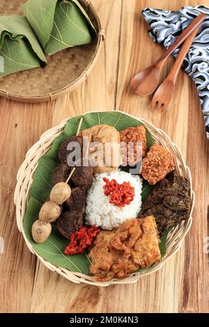 Nasi Jamblang or Sega Jamblang, Cirebon Mix Rice Wrapped with Teak Leaf. Served with Various Side Dish. TOp View on Wooden Table Stock Photo