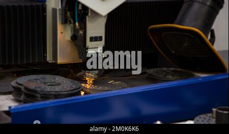 CNC laser cutting machine cutting holes on metal workpiece in factory. Industrial manufacture. Stock Photo