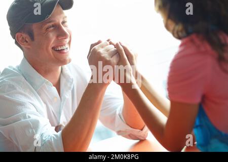 Intimate and comfortable. A handsome young man holding his girlfriends hand and looking at her lovingly. Stock Photo