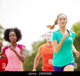 She sprints with a determined spirit. a group of female athletes running outdoors. Stock Photo