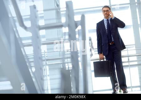 Ive got a meeting to attend...Handsome mature businessman on his mobile while walking. Stock Photo