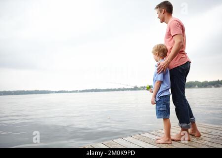 Father and son. A father teaching his son how to fish with copyspace. Stock Photo