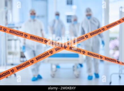 Medical doctors in a covid protected room. Biohazard team behind quarantine tape barrier. Biologist colleagues working in prohibited hospital room Stock Photo