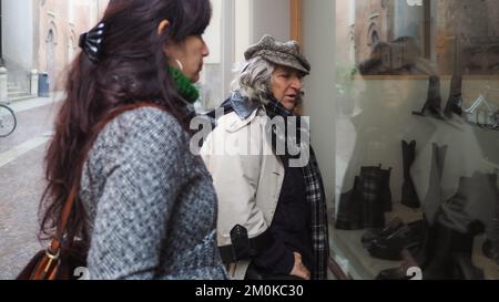 latino young adult and senor east european women looking shoes at shop display in city center in Italy Stock Photo