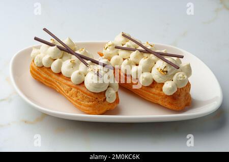 Two eclairs with white custard on whhite plate Stock Photo