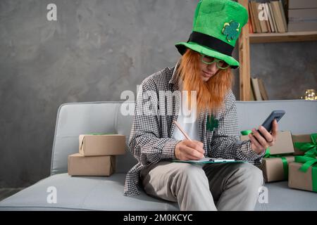 start up small business having order from customer on mobile phone at home shop. Online shopping on St.Patricks day. freelance man seller noting order Stock Photo