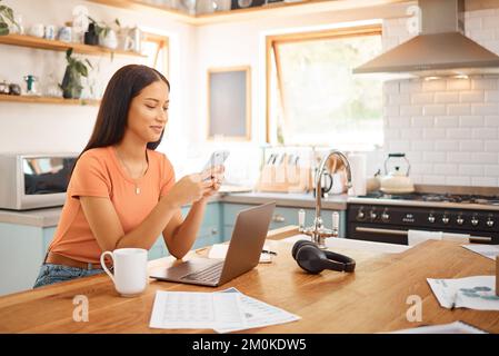 Young happy mixed race businesswoman using a phone while working from home. One content hispanic woman using social media on her cellphone while using Stock Photo