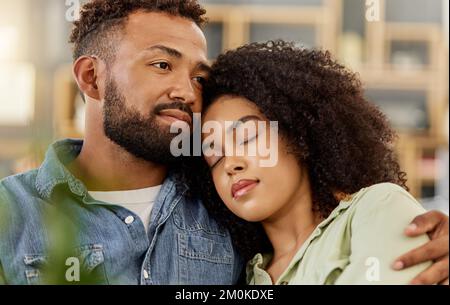Young mixed race couple embracing while resting on the couch at home. Content hispanic boyfriend and girlfriend sitting on the sofa together Stock Photo
