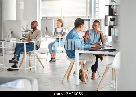 Two businesspeople having a meeting together in an office at work. Young african american businesswoman talking to an asian businessman . Colleagues Stock Photo