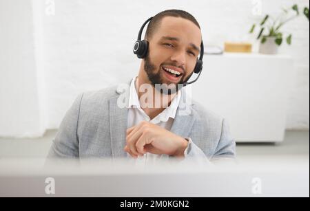 Young happy mixed race male call center agent answering calls while wearing a headset at work. Hispanic businessman talking on a call while working on Stock Photo