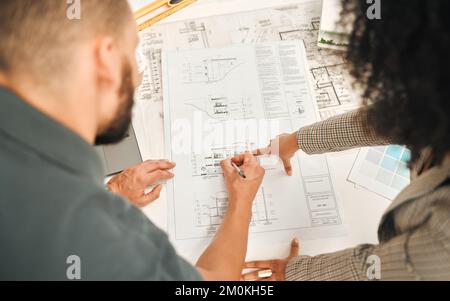 Architects working on a blueprint from above. Businesspeople writing on a building plan. Coworkers working on architect plan. Businessman working with Stock Photo