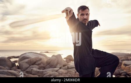 Man, sword and zen thai chi balance on beach for fitness training, chakra healing or spiritual energy. Thai wellness workout, meditation exercise and Stock Photo
